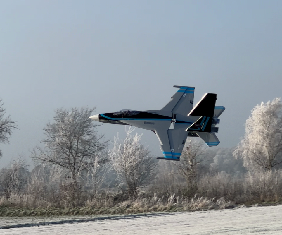 F-18 im Vorbeiflug vor wunderschöner Winterwetterkulisse mit Schnee.