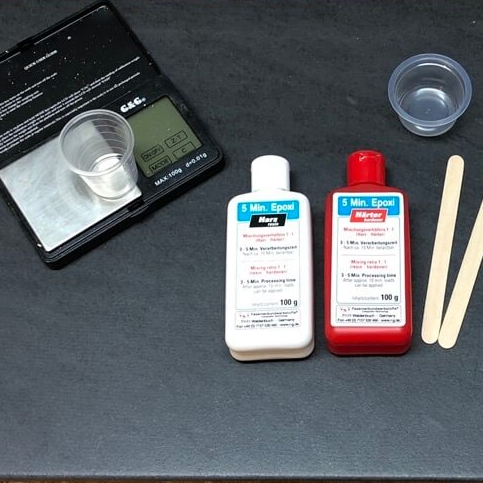 5-Min-Epoxy. Der Klassiker in der roten und weißen Flasche. Den gibts von mehreren Herstellern. Vmtl. gelabelt. 5-Minuten Epoxy oder Epoxidharz 2-Komponenten-Kleber