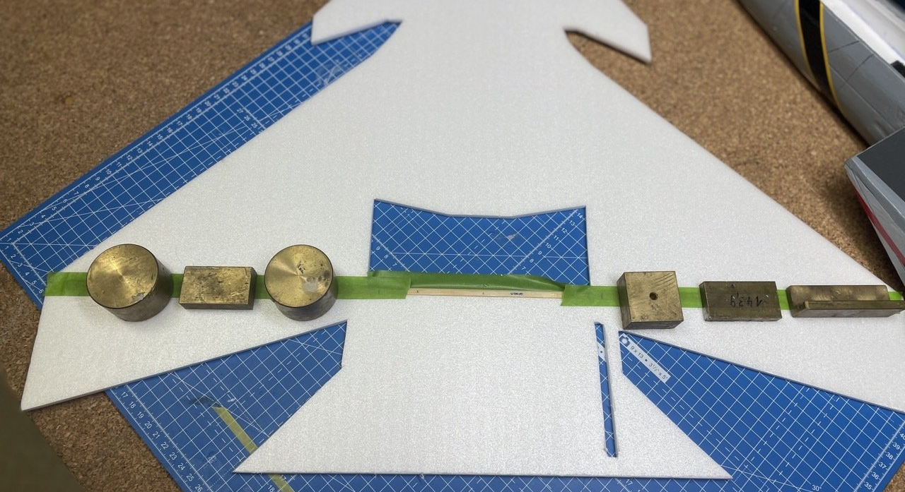 Der mit Epoxy eingeklebte Kiefernholm wird zum Trocknen mit Gewichten beschwert, so dass sich die Rumpfplatte nicht verziehen kann. verklbeter Stabilisierungsholm mit Gewichten beschwert