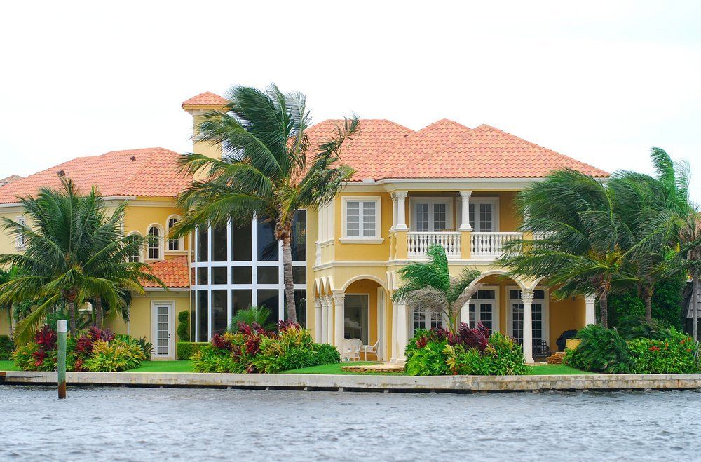 Two Story Yellow House With Palm Trees on Ocean Frontage