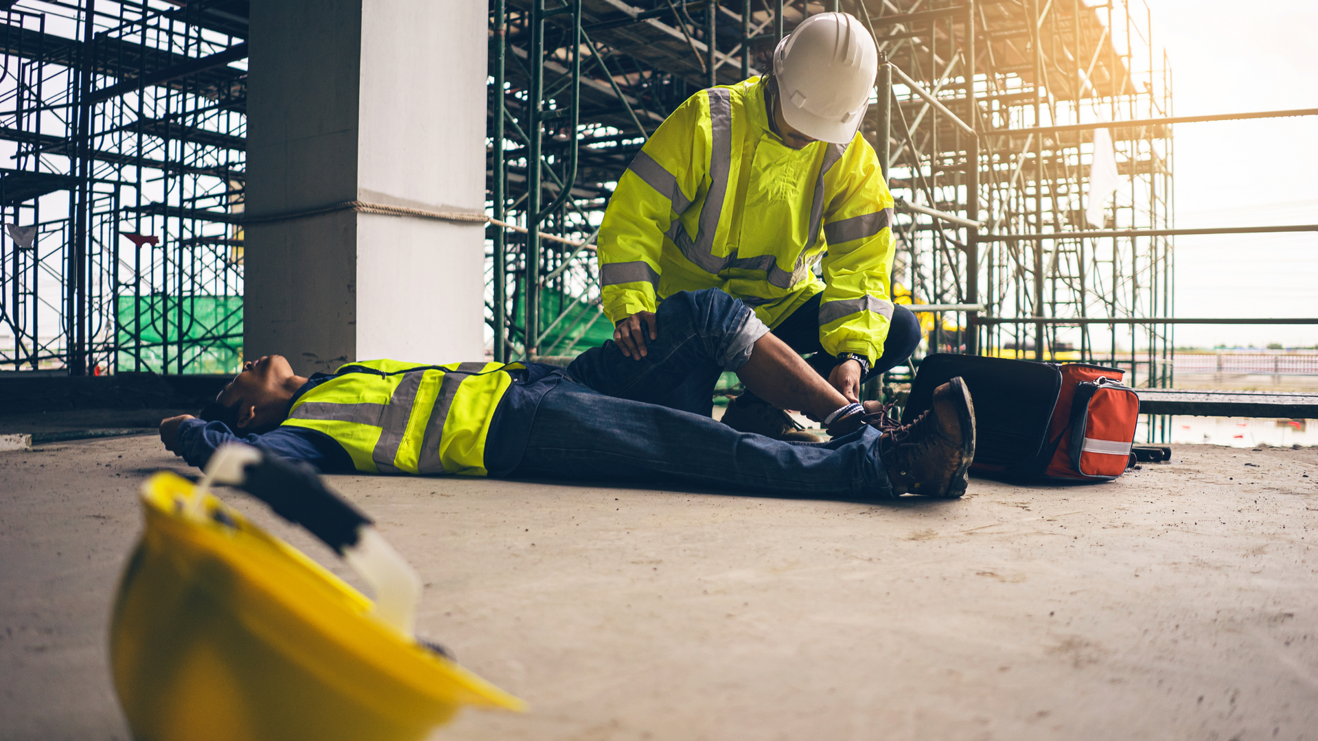 Shows worker collapsed at building site receiving first aid