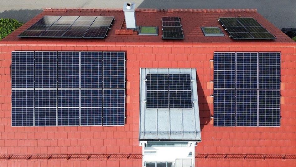 Rotes Hausdach, dass eine installierte Photovoltaik-Anlage (PV-Anlage) zeigt