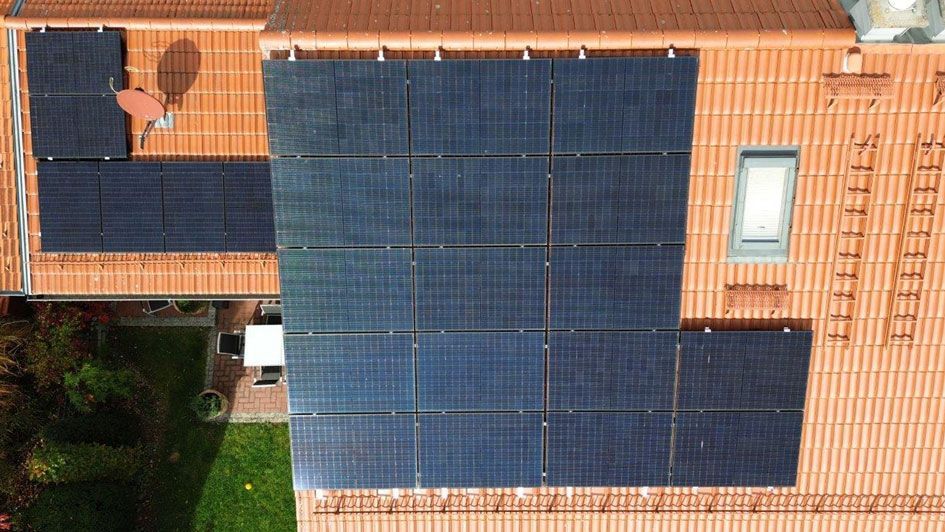 Rotes Hausdach, dass eine installierte Photovoltaik-Anlage (PV-Anlage) zeigt