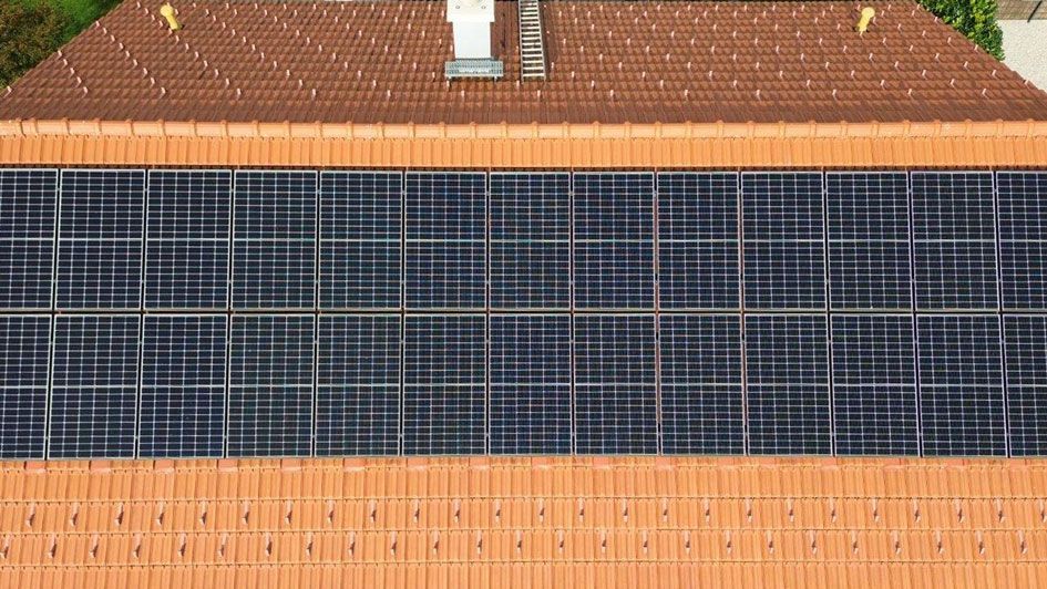 Rotes Hausdach, dass eine installierte Photovoltaik-Anlage (PV-Anlage) zeigt