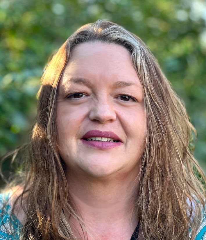 Head and shoulders of a woman with long blonde plaited hair