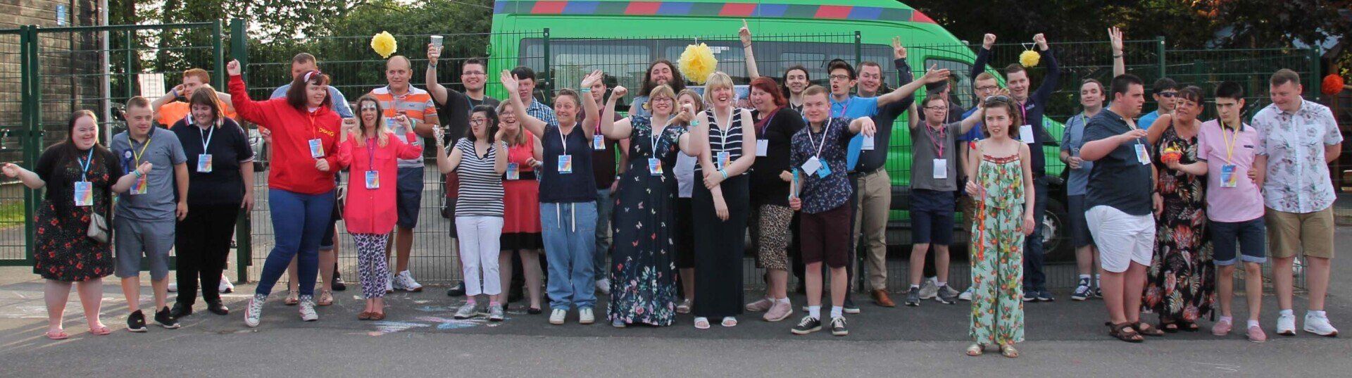 A group photo of many people in the school playground waving