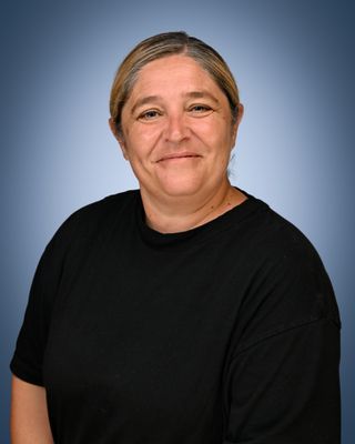 Head and shoulders of a woman with dark hair tied back