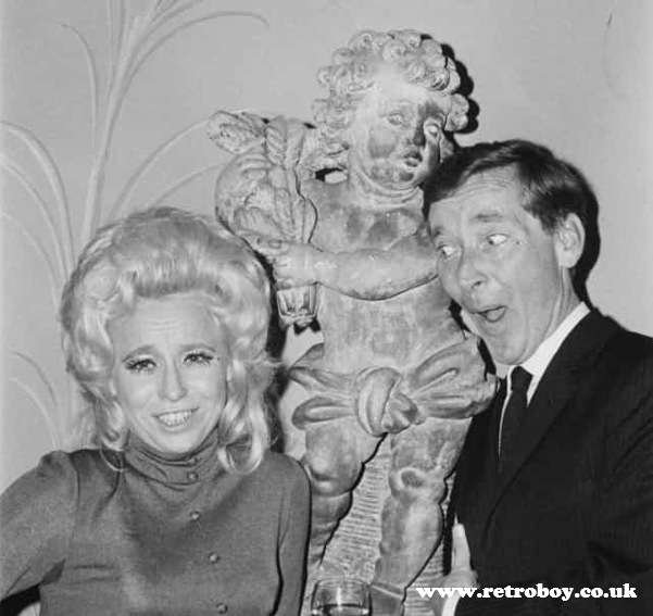 Close friends Kenneth Williams and Barbara Windsor creating mischief with a cherub (early 80's?).