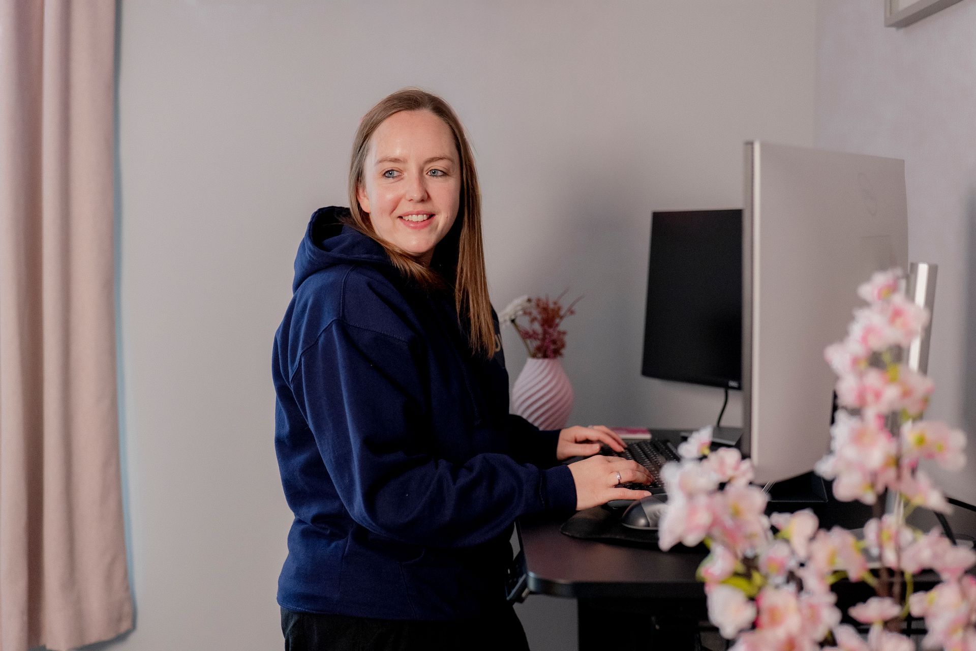 Chrissy working at a standing desk looking to the side of the camera