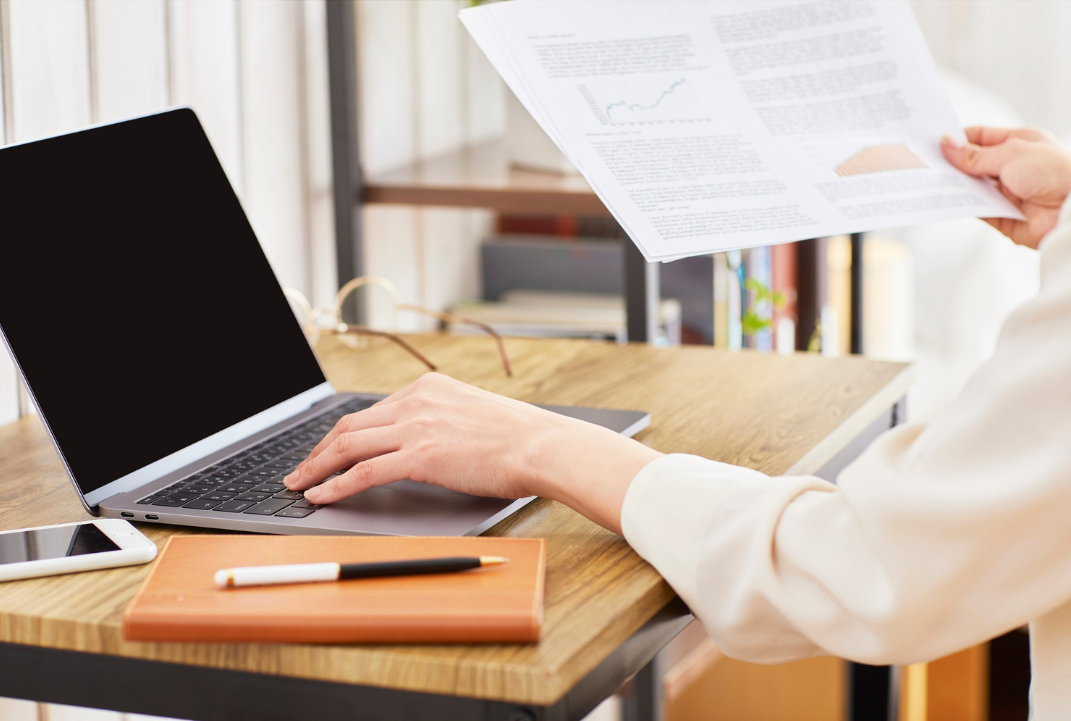 Person at a desk with laptop, notebook and pen