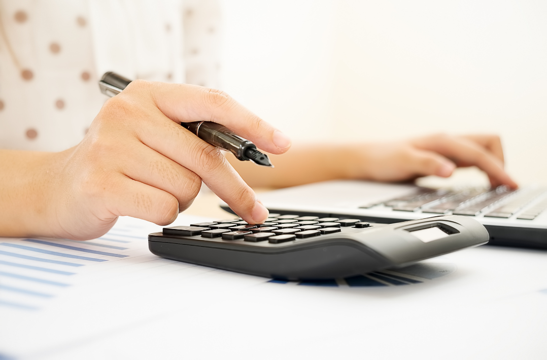 Person holding a pen and sPerson holding a pen and using two calculators
