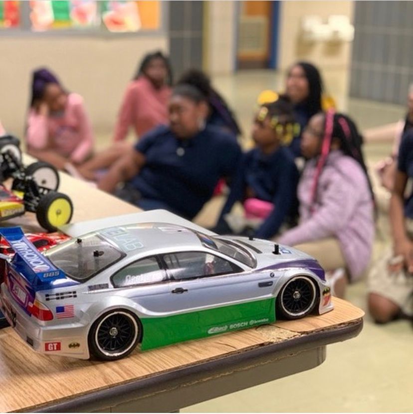 Students sitting on the floor in a classroom with the focus on cars.