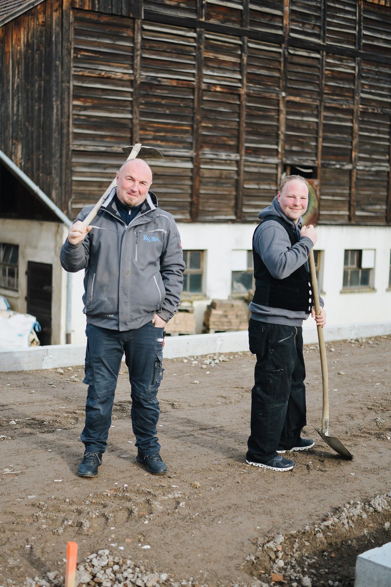 wei Bauarbeiter der RS Bau & Immo GmbH stehen auf einer Baustelle.