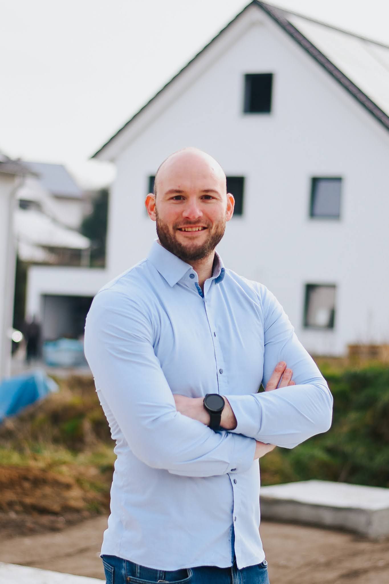 Ein Mann mit verschränkten Armen und einem blauen Hemd