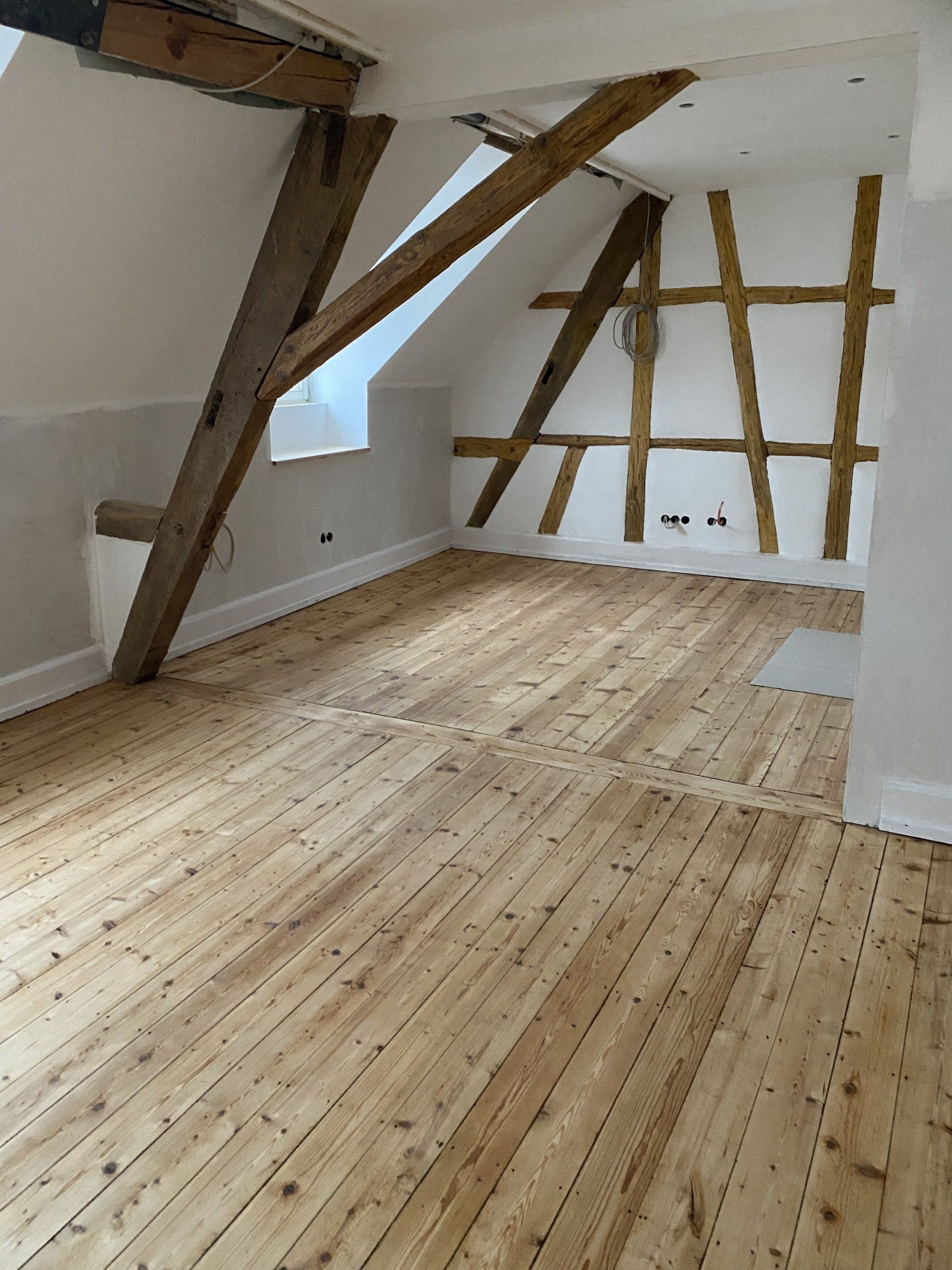 Renoviertes Dachgeschoss mit Holzfußboden und sichtbaren Balken in Helmstadt – Innenausbau durch RS Bau & Immobilien.