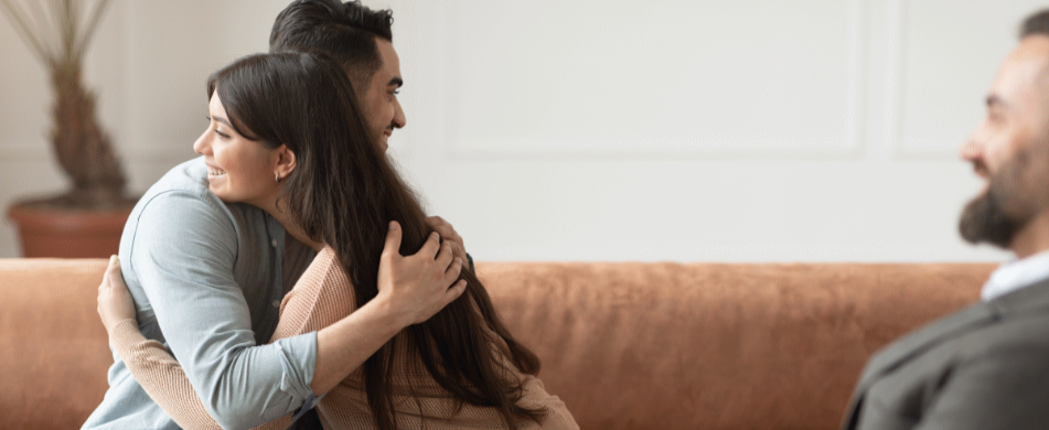 RLTMC Services hero image, a couple sitting on the counsellor's couch, embracing with a happy expression on both their faces.