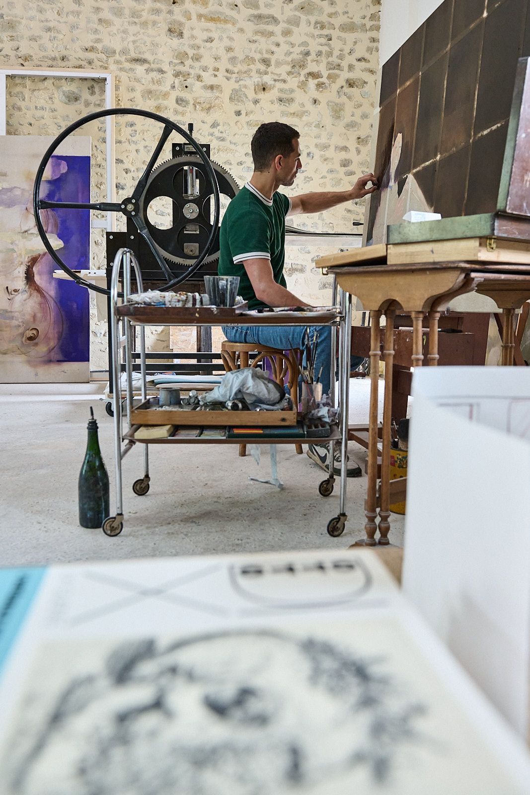 Djabril Boukehnaissi devant une de ses peintures à l'huile avec sa presse à gravure en arrière plan