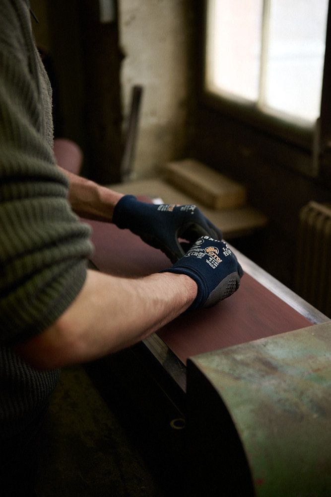 Main d'artisan sur une meule à ruban