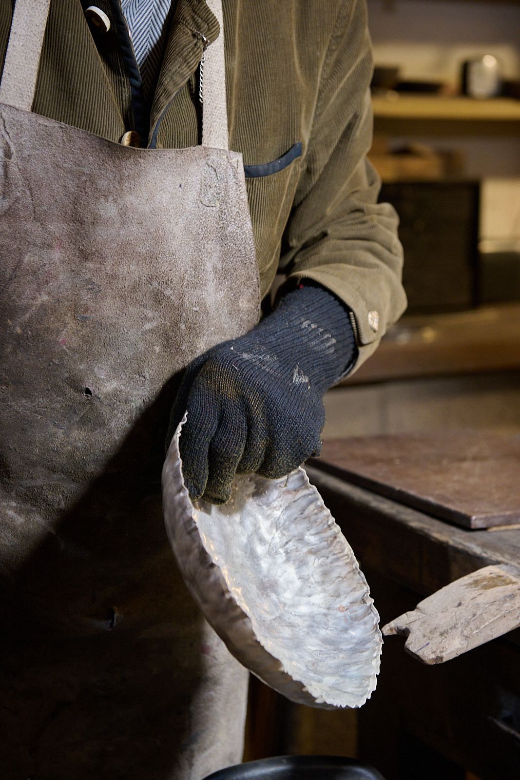 Artisan utilisant un gant pour tenir un bol en argent chauffé