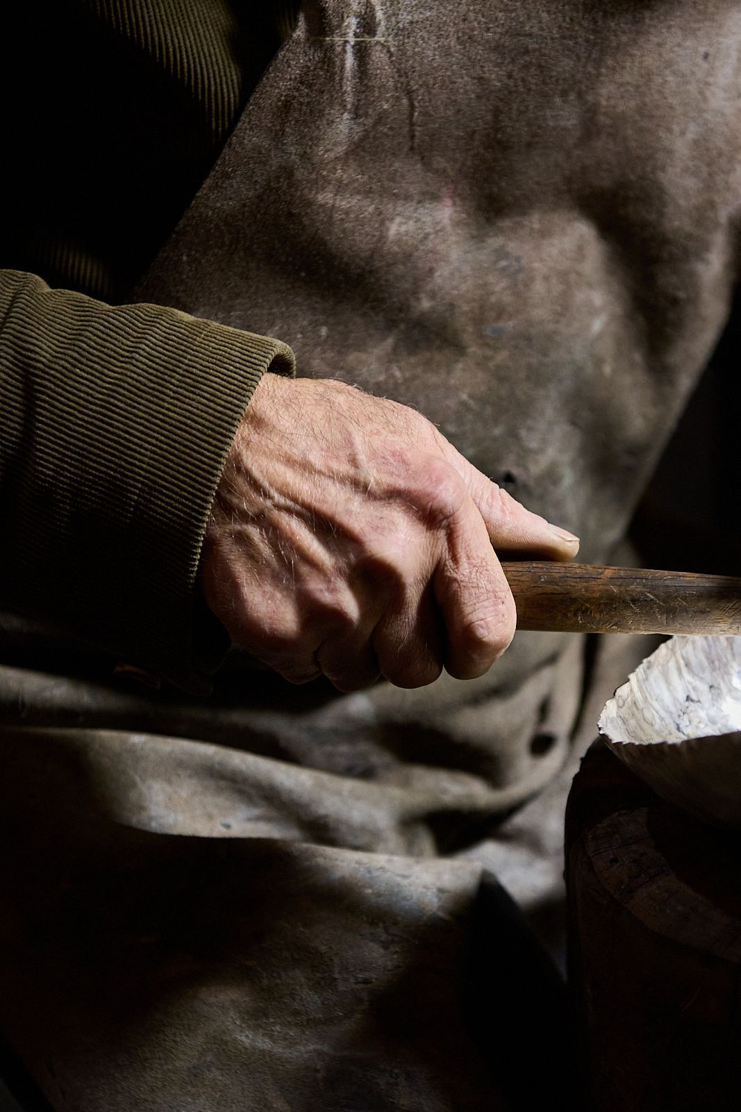 main artisan tenant un marteau et tablier en cuir usé