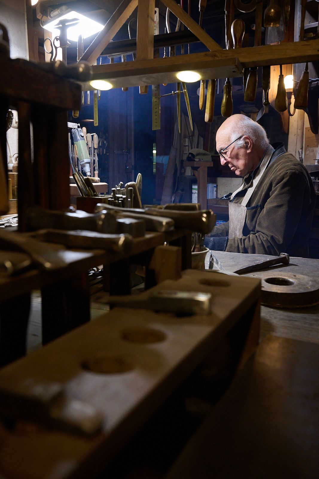 Vieil artisan au travail dans son atelier entouré de ses outils
