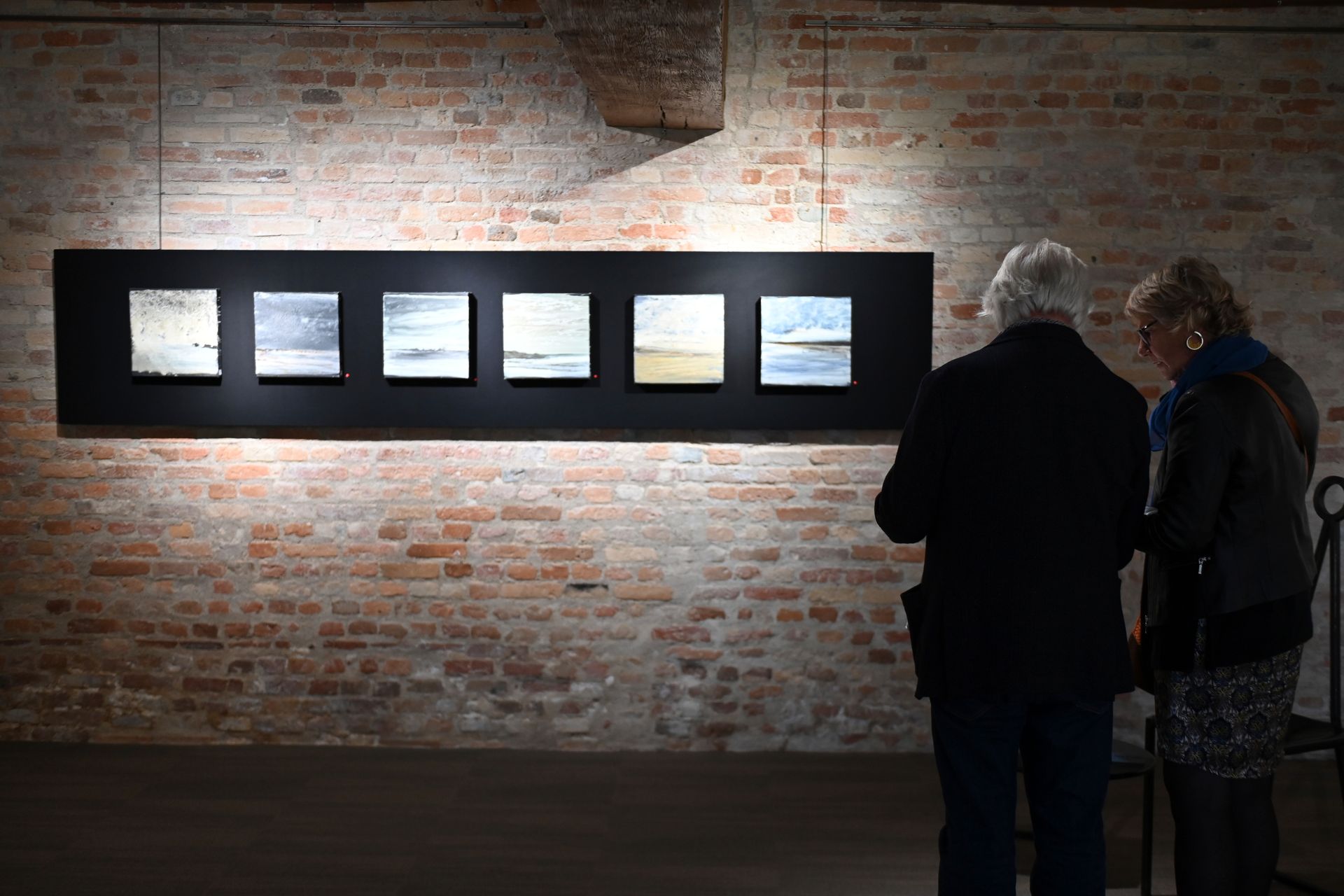 Couple face à une série de tableaux lors d'un vernissage