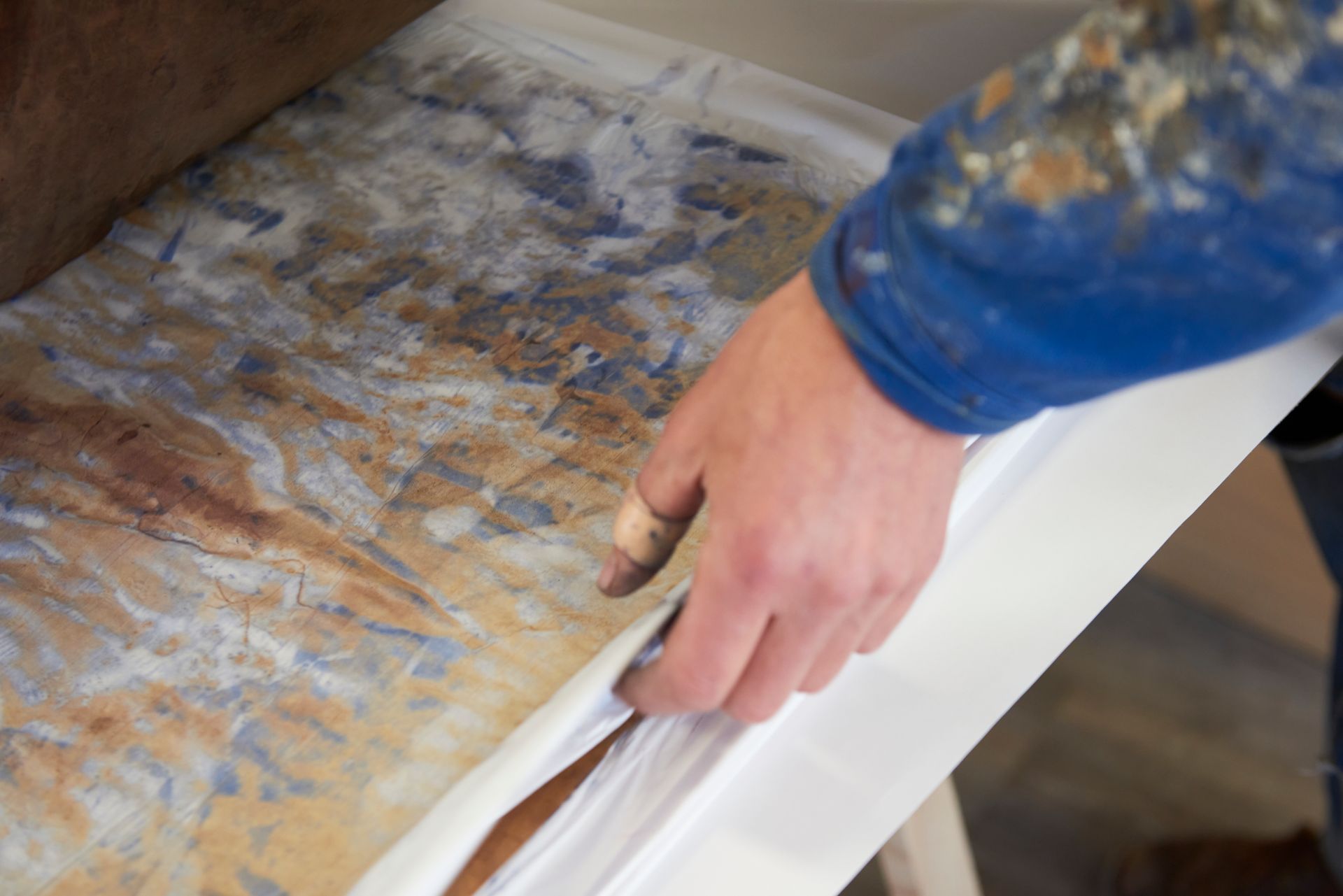Les main de Clément Barbier sépare des feuilles de papier qui ont servià sécher la teinture sur bois
