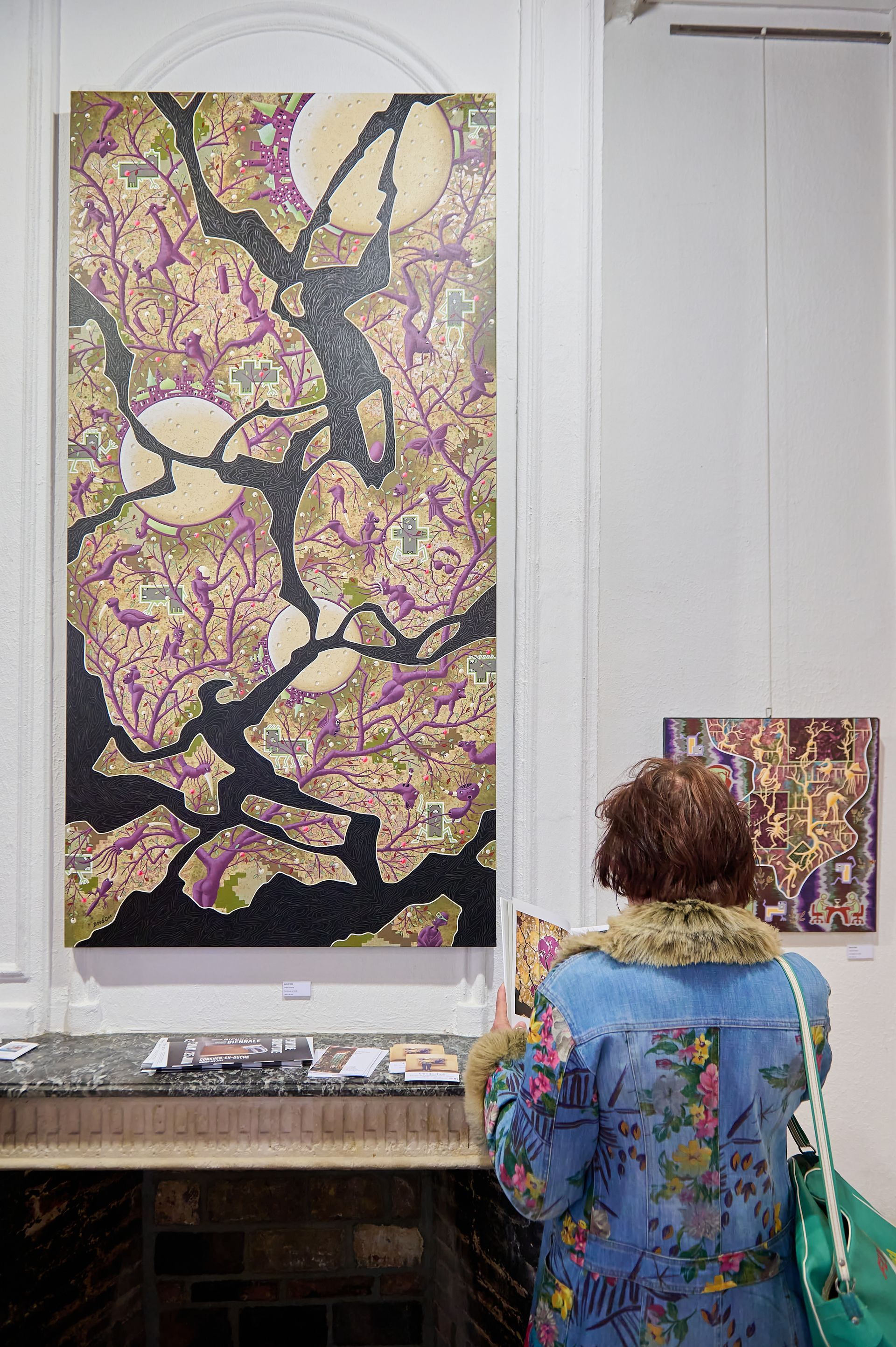 Personne portant un manteau à motif devant des oeuvres au motif similaire