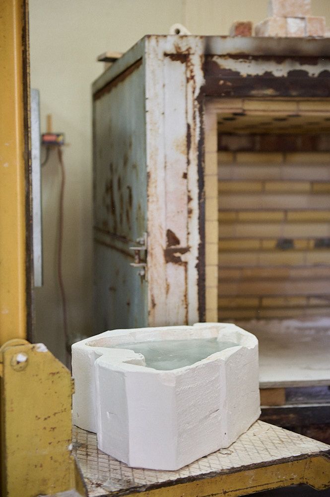 Pièce en verre encore dans son moule sur un palanquin devant un four de fusion