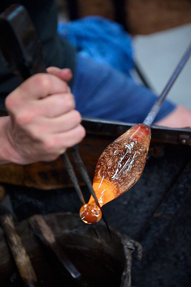 Etirement du verre chaud par un artisan