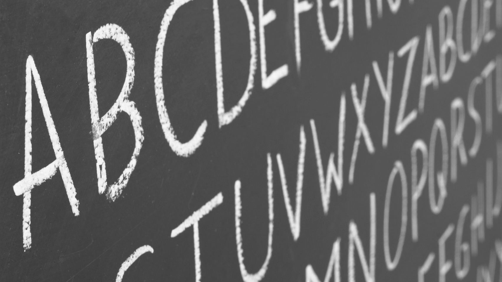 Schmuckbild einer Tafel, auf der mit Kreide das Alphabet steht.