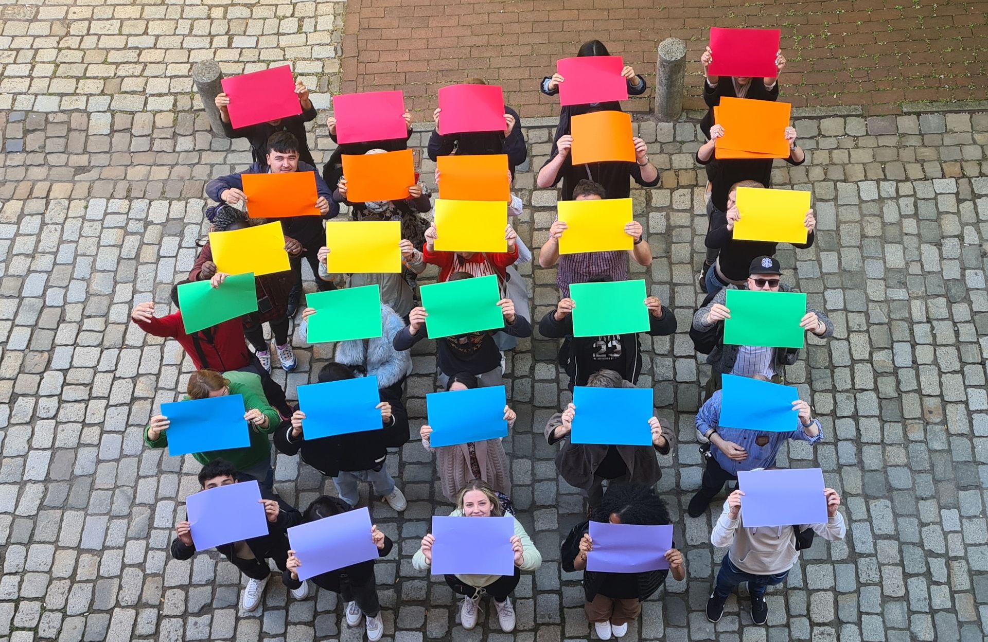 Foto von Studierenden, die Plakate in Regenbogenfarben hochhalten