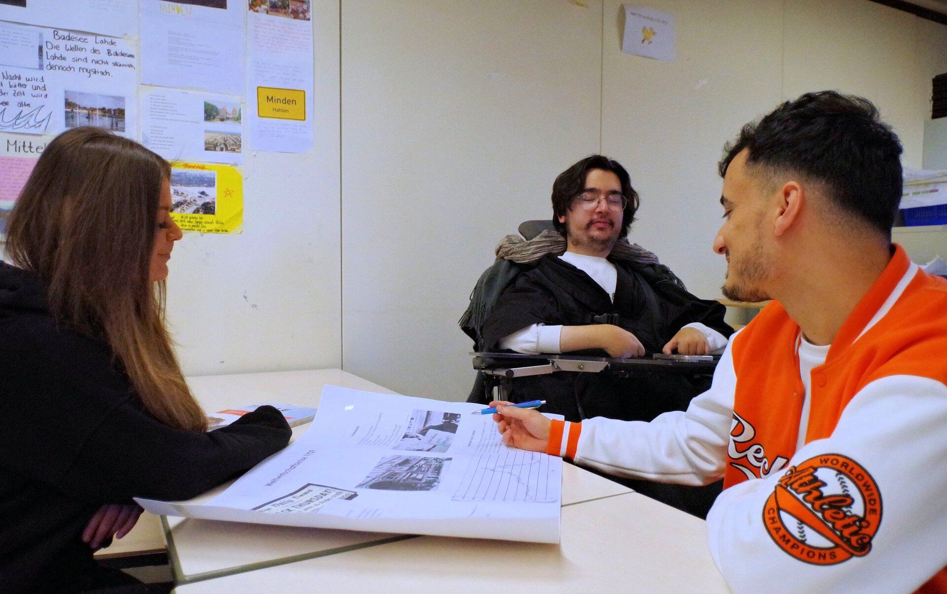 Foto von drei Studierenden, die an einem Plakat arbeiten