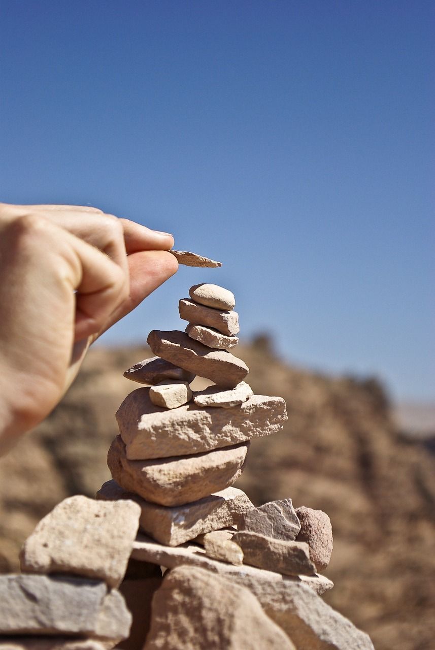 Image of a pile of rocks with a someone placing another rock on top of it.