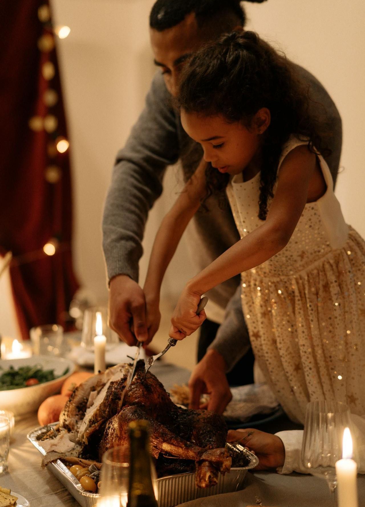 Image of a man and a girl working together to carve a turkey.
