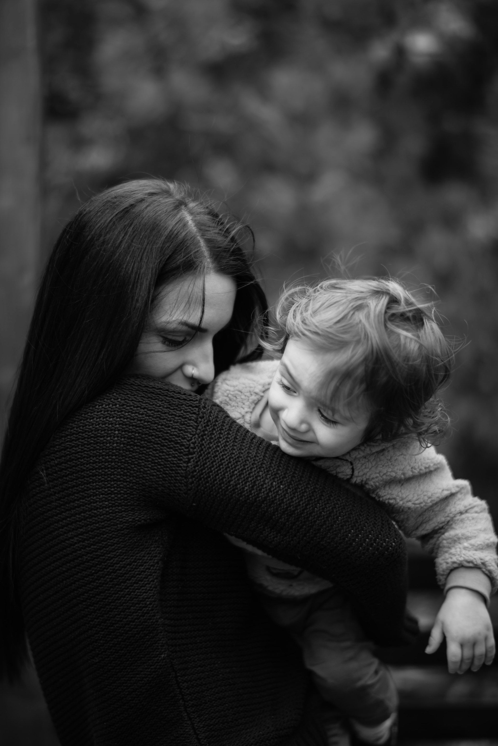 A woman struggling to maintain her hold on a playful child.