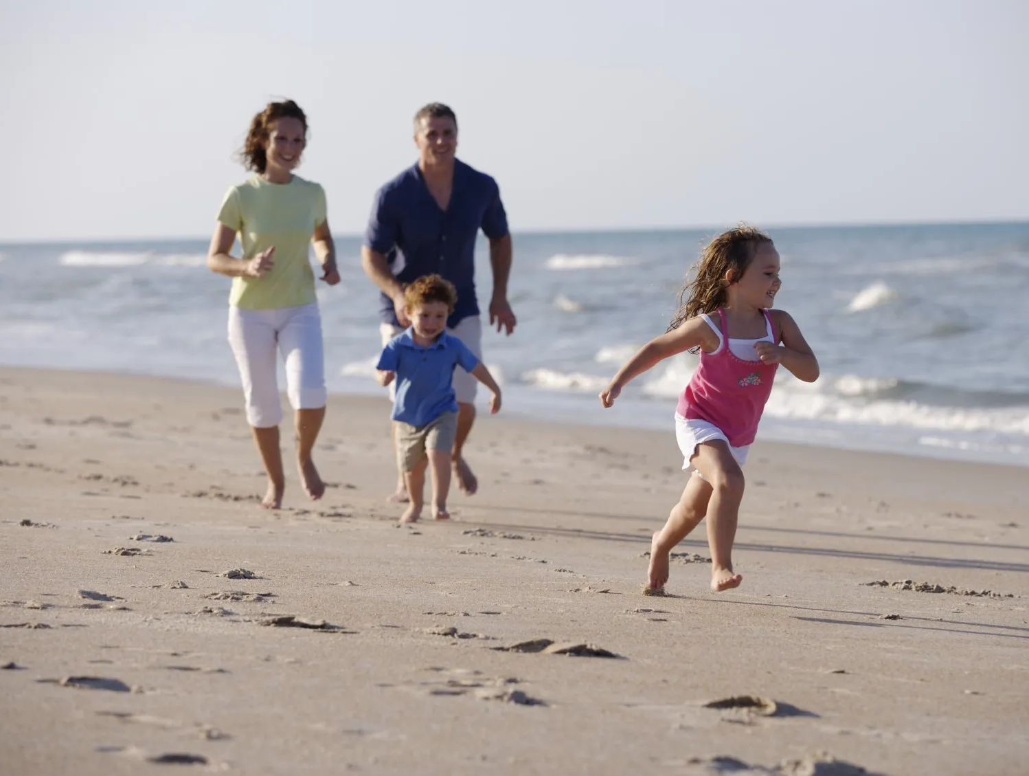 Familie läuft am feinen Sandstrand