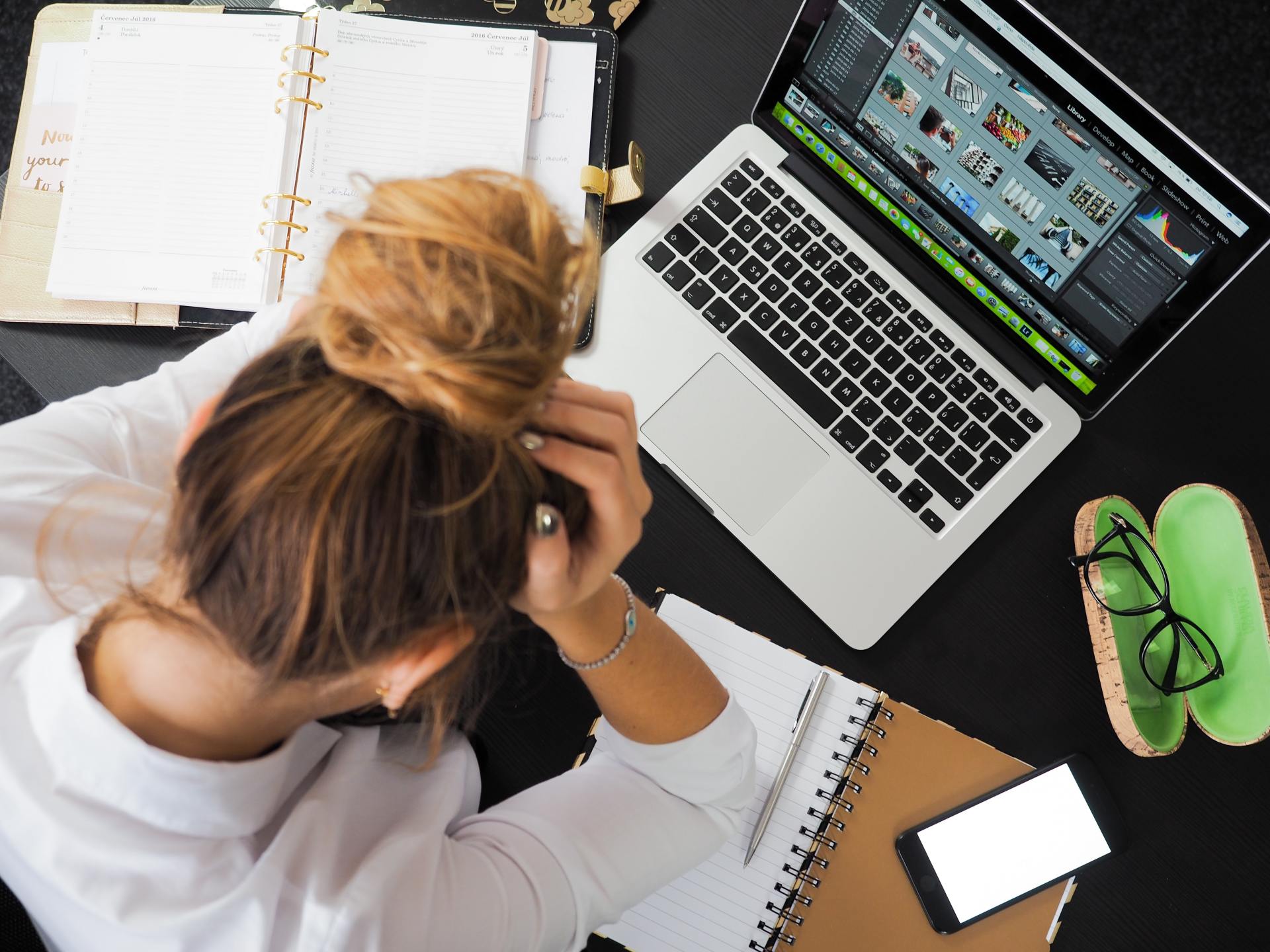 Stressed out female worker at her desk holding her head.