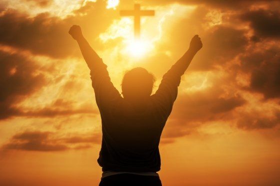 a person cheering with their arms in the air with a cross above them