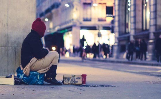a homeless person sitting on the streets of a city
