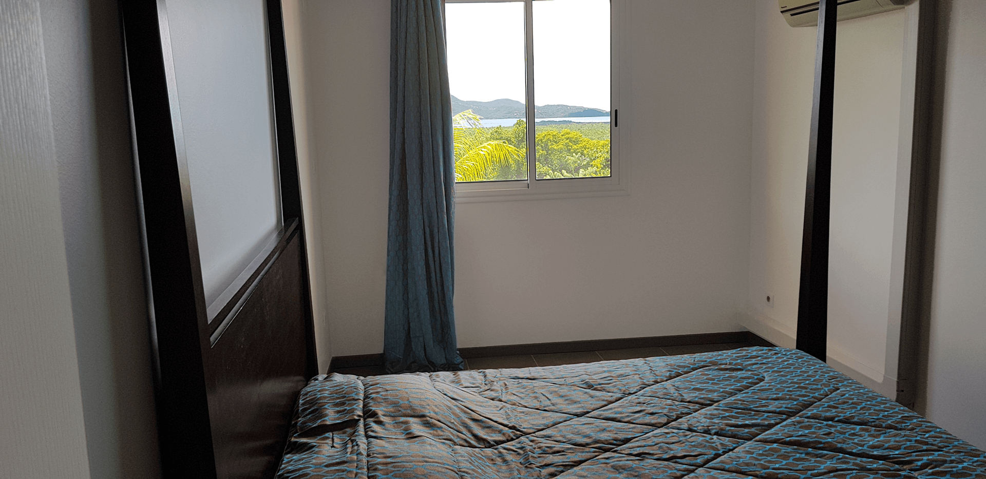 Lit à baldaquin. Chambre climatisée. SurlaBaie.fr Location F2 sur Baie de Fort-de-France Martinique. Location Saisonnière Appartement F2 à louer à la semaine avec vue sur la Baie de Fort de France à Ducos. Location de vacances en Martinique. Maison avec piscine et jardin avec vue sur la Baie de Fort-de-France