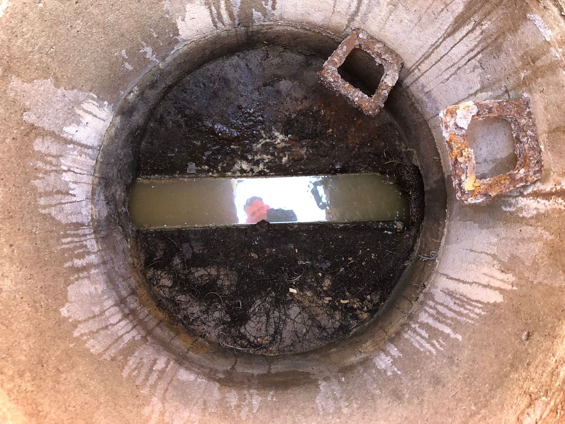 Verschlammter Übergabeschacht. Versandeter und verstopfter Schacht zum Siel in der Straße.