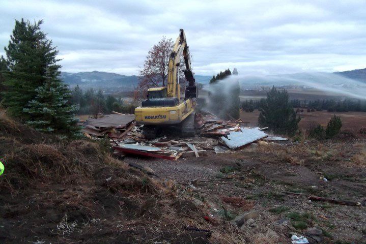 Crane Demolishing a Building Overlooking a Mountainous Landscape
