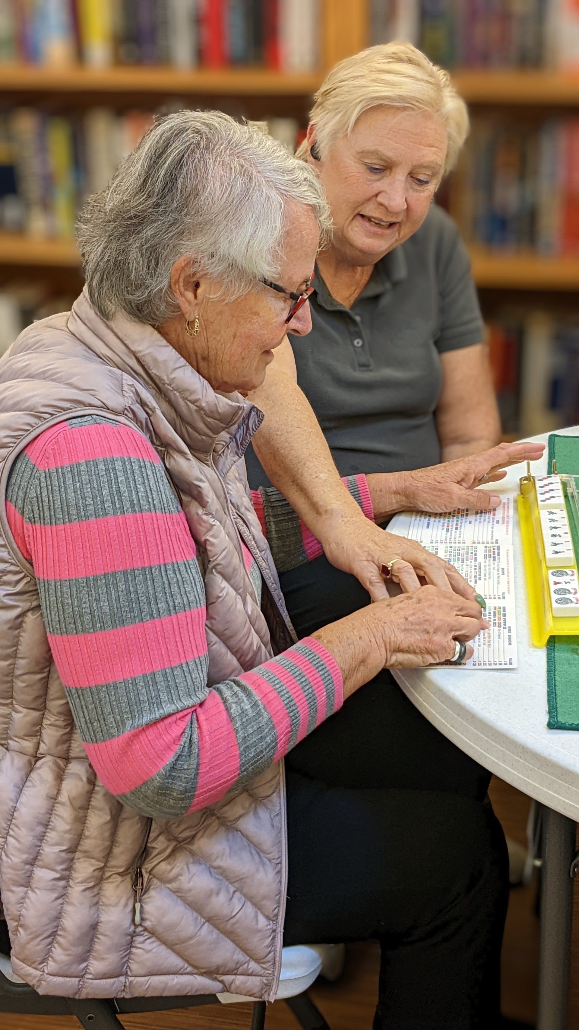 Joan coaching one Mah Jongg player regarding hand to play