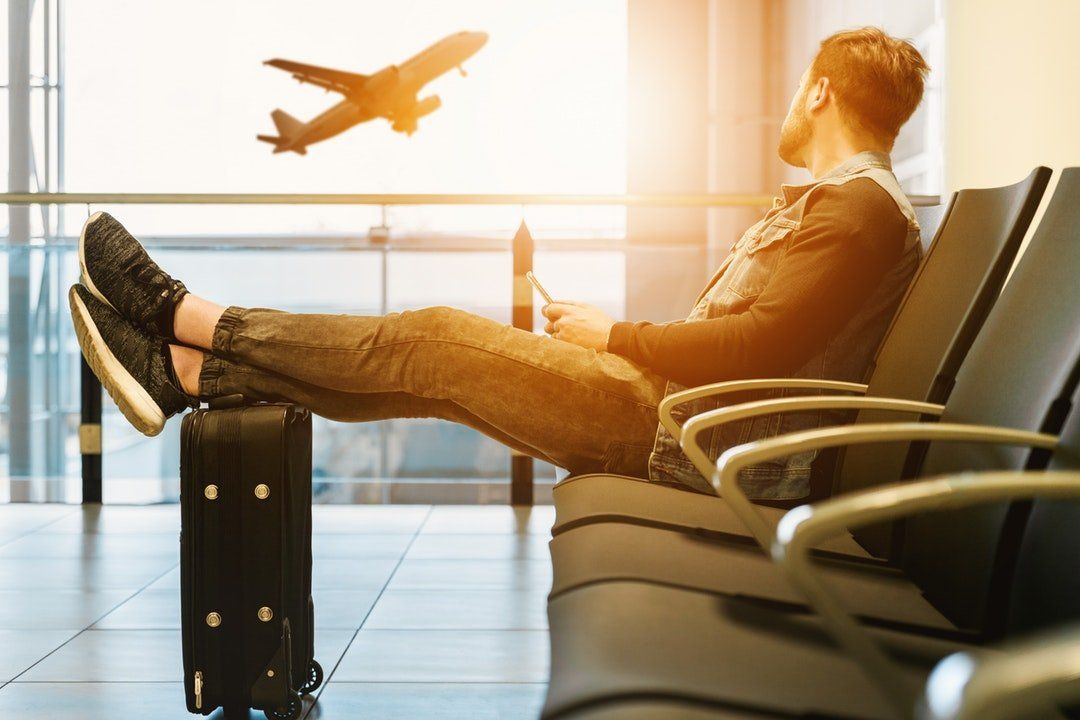 Person sitting in the airport looking at a plane taking off