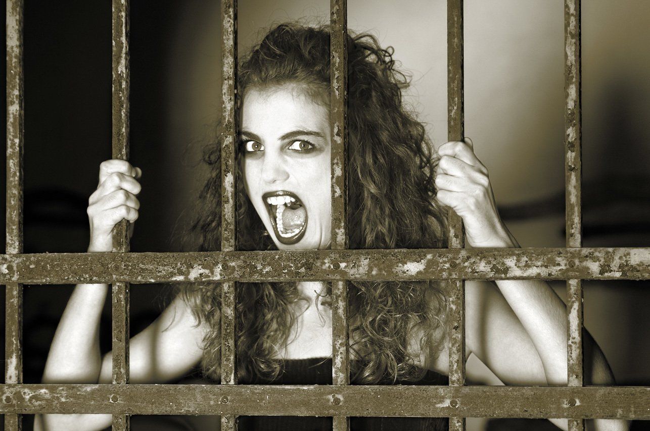 Thierry Aguiar, photographe Bordeaux : Portrait d'Albane derrière une grille, les mains agrippées au barreau, criant.s