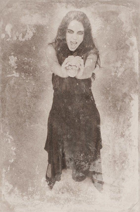 Thierry Aguiar : Photo ancienne abîmée en noir et blanc d'Albane en gothique, debout en robe noire,  des bougies et un crâne posés à ses pieds. Tirage imitation gélatino-bromure d’argent.
