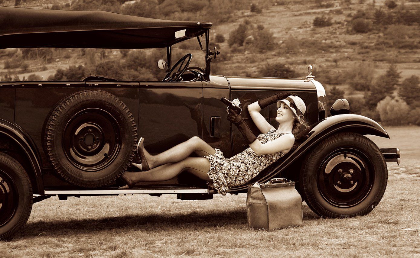 Albane en Bonnie avec un chapeau en paille et des bas allongée sur le marche-pieds d'une Citroën C4 Torpedo conduite à droite