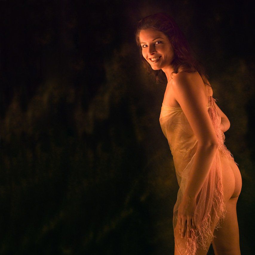 Thierry Aguiar : photo d'Aurélie nue, souriante, debout, de trois-quart dos, portant un voile transparent,  éclairée par des bougies.