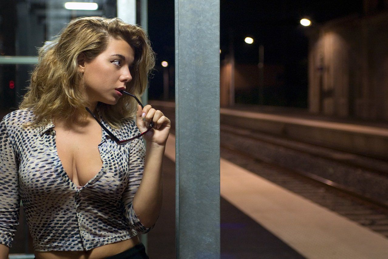 Aguiar Thierry : photo couleur de face de Cindy de secret story, adossée à une cabine téléphonique, sur un quai de gare, la nuit, l'air rêveur.
